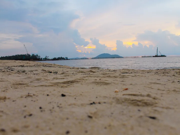 Pantai Pasir Panjang di Singkawang dengan perairan dan struktur laut di kejauhan.